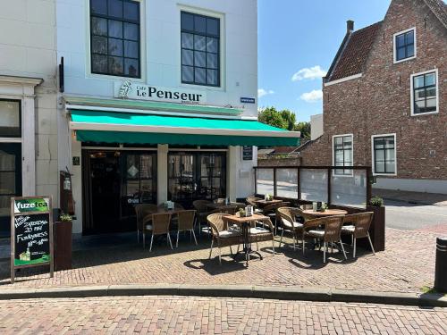 a restaurant with tables and chairs in front of a building at Le Penseur in Middelburg