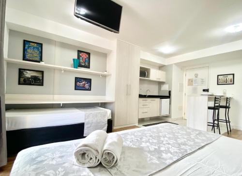 a bedroom with two white beds and a kitchen at Flat WiseSP - Expo Anhembi in Sao Paulo