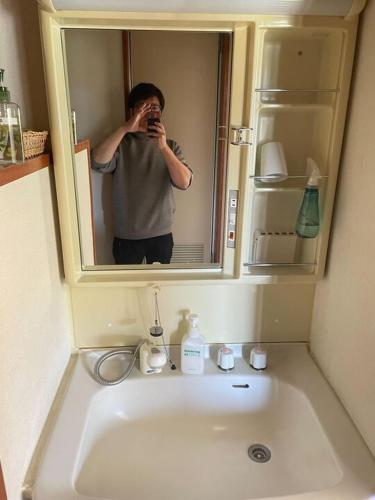 a man taking a picture of a bathroom sink at 入山登 in Hakuba