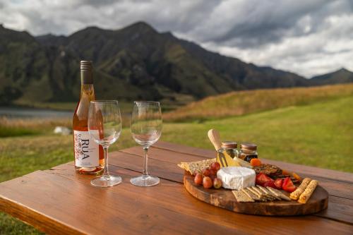 a bottle of wine and two glasses on a wooden table at Glam Camping Queenstown in Queenstown