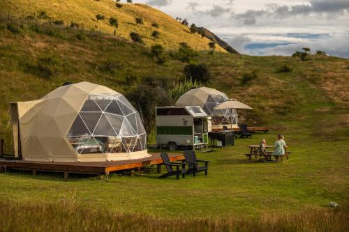 two people sitting at tables in a field with tents at Glam Camping Queenstown in Queenstown