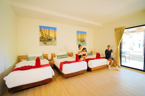 a bedroom with three beds and people sitting on them at Villa Cha Cha Chaolao Beach Resort in Chao Lao Beach