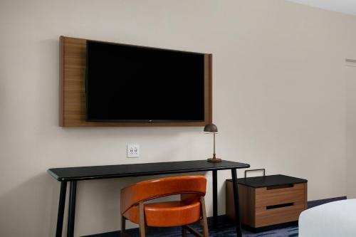 a desk with a chair and a television on a wall at Fairfield by Marriott Inn & Suites Lewisburg in Lewisburg