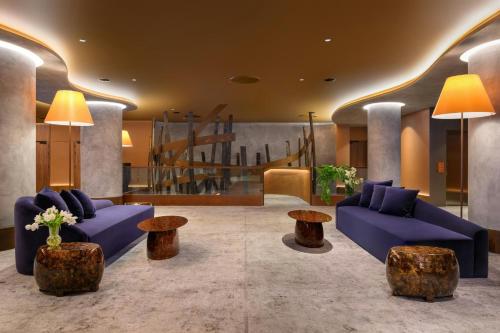 a living room with blue couches and tables and stairs at Forte de Gaia, Autograph Collection in Vila Nova de Gaia