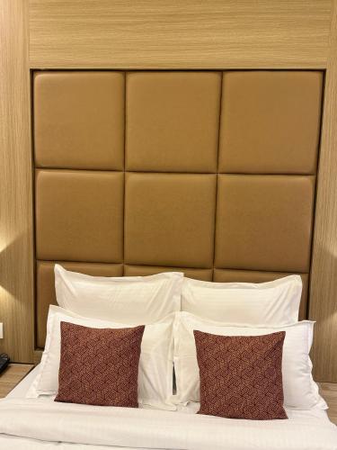 a bed with white pillows and a large headboard at Hotel Bellamont in Mumbai