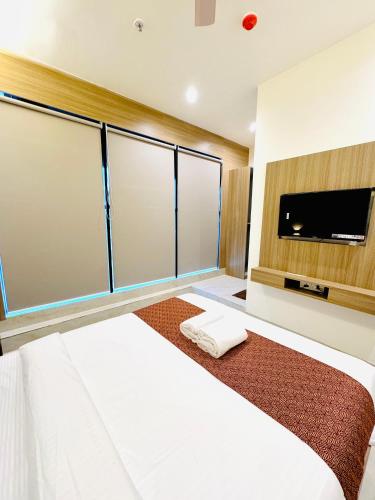 a bedroom with a large bed and a flat screen tv at Hotel Bellamont in Mumbai