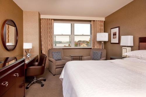 a hotel room with a bed and a desk and chair at Sheraton Portsmouth Harborside Hotel in Portsmouth