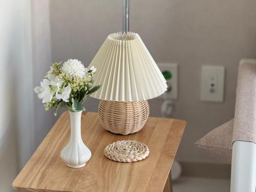een vaas met bloemen en een lamp op een tafel bij The Comfort in Seoul