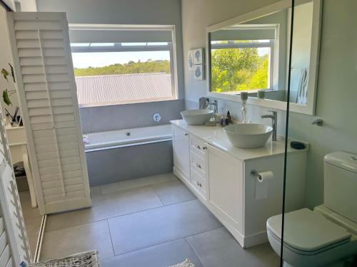 a bathroom with two sinks and a tub and a window at The Pijper House - Brackenridge Eco Estate Plettenberg Bay in Plettenberg Bay