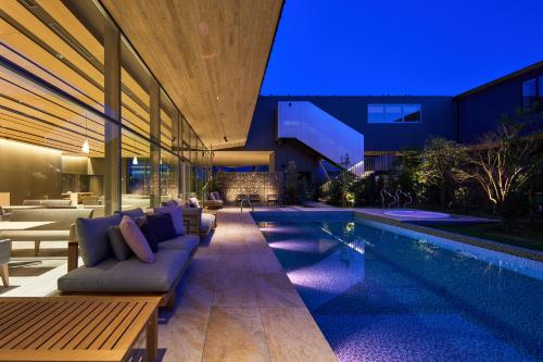 a swimming pool next to a house with a couch at The Meibia Miyazaki in Miyazaki