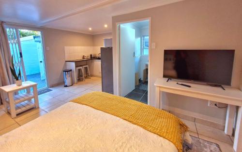 a bedroom with a bed and a flat screen tv at Ivy Place Studio Apartment in Cape Town