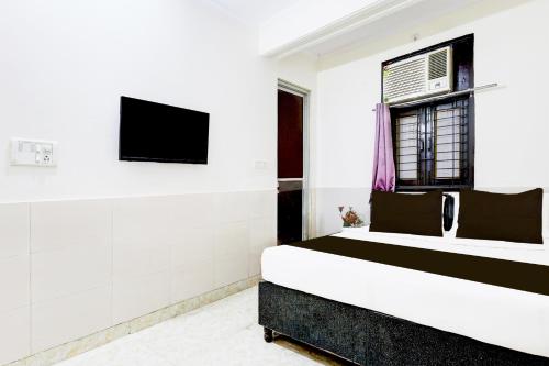 德里Super Hotel O Fazalpur的一间卧室，墙上有一张床和一台电视