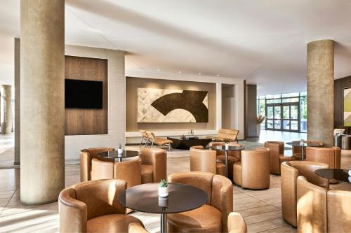 a lobby with tables and chairs and a tv at AC Hotel by Marriott Irvine in Irvine