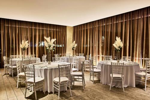 a room with tables and chairs with white tablecloths at AC Hotel by Marriott Irvine in Irvine