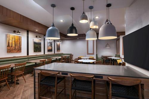 ein Restaurant mit Tischen und Stühlen und Pendelleuchten in der Unterkunft Fairfield by Marriott Inn & Suites Hillsboro in Hillsboro