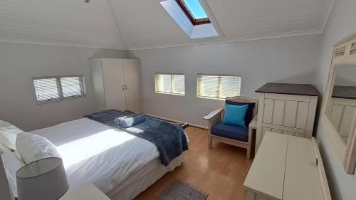 ein Schlafzimmer mit einem Bett und einem blauen Stuhl in der Unterkunft 112 The Dunes in Keurboomstrand