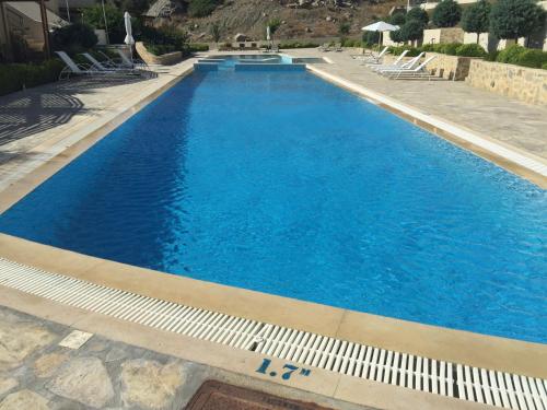 a large swimming pool with blue water and chairs at Lagada Resort in Makry Gialos