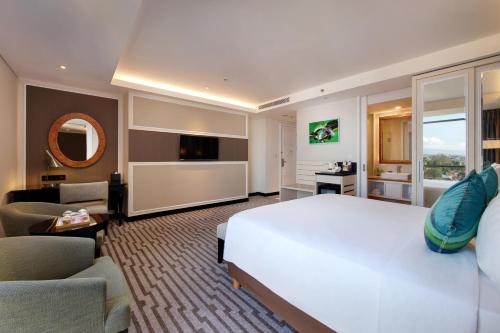 a bedroom with a large white bed and a living room at Swiss-Belboutique Yogyakarta in Yogyakarta