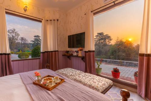 a bedroom with a bed and a large window at Seclude Tea Estate, Palampur in Pālampur