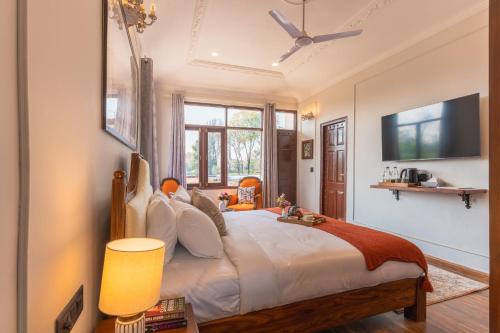 a bedroom with a large bed with a tv on the wall at Seclude Tea Estate, Palampur in Pālampur