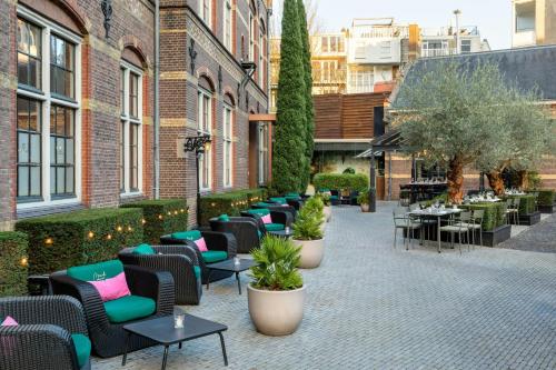 an outdoor patio with chairs and tables and trees at The College Hotel Amsterdam, Autograph Collection in Amsterdam