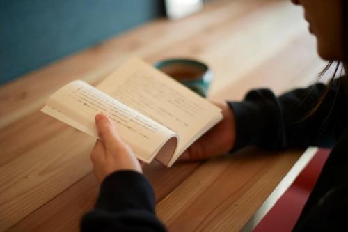 a person reading a book on a table at KARASUYA GuestHouse in Takasaki