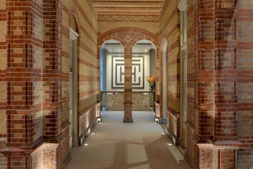an empty hallway in a brick building with lights at The College Hotel Amsterdam, Autograph Collection in Amsterdam