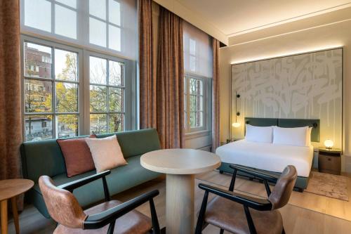a hotel room with a bed and a table and chairs at The College Hotel Amsterdam, Autograph Collection in Amsterdam