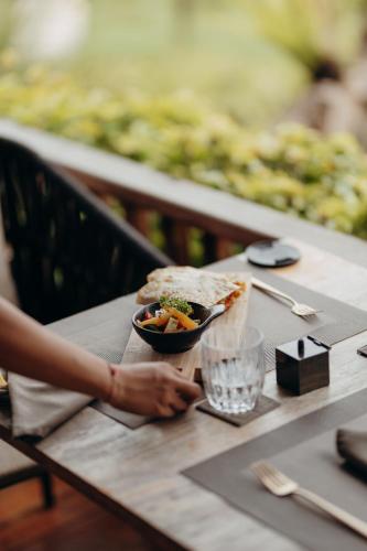 a person sitting at a table with a bowl of food at East Bali Volcano View Resort & Spa - Adults Only Area in Karangasem