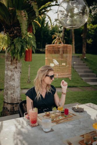 a woman sitting at a table with food at East Bali Volcano View Resort & Spa - Adults Only Area in Karangasem