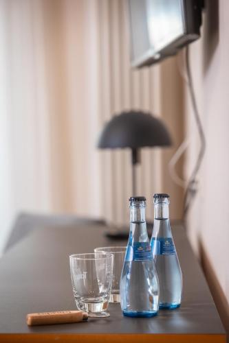 two bottles of water and a glass on a table at Roots Hotel Restaurant in Gomaringen