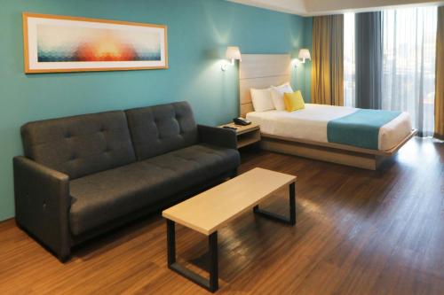 a hotel room with a bed and a couch at City Express Suites by Marriott Tijuana Rio in Tijuana