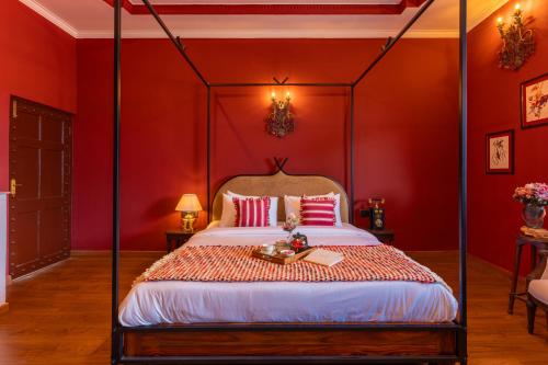 a bedroom with a canopy bed with red walls at Seclude Tea Estate, Palampur in Pālampur