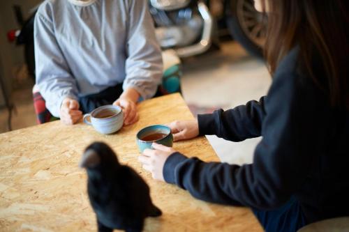 a couple of people sitting at a table with a bird at KARASUYA GuestHouse in Takasaki