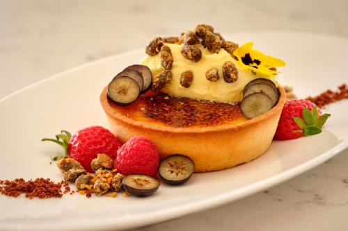 a dessert with fruit and nuts on a white plate at The College Green Dublin Hotel, Autograph Collection in Dublin