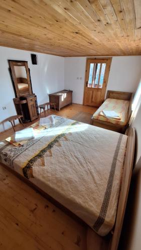 a bedroom with a large bed with a wooden ceiling at Къща за гости Хитър Петър in Apriltsi