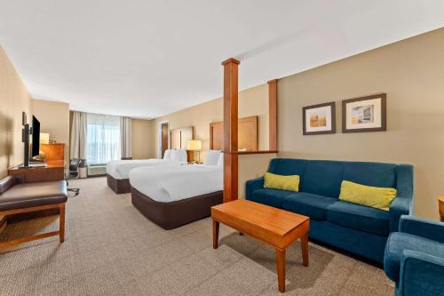 a hotel room with a bed and a blue couch at Comfort Inn & Suites Avera Southwest in Sioux Falls
