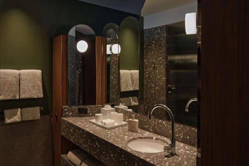 a bathroom with a sink and a large mirror at The EVE Hotel Sydney in Sydney