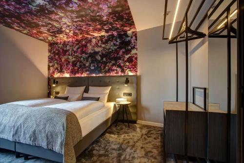 a bedroom with a large bed with a painting on the wall at Vienna House Easy by Wyndham Hamburg City in Hamburg