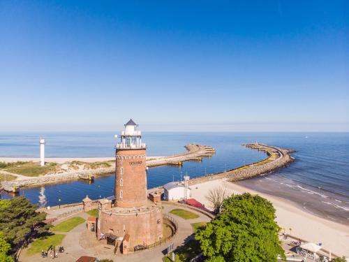 a lighthouse on a beach next to the ocean at Apartamenty Fenomen - Premium Porto Nadmorskie Tarasy w Kołobrzegu in Kołobrzeg