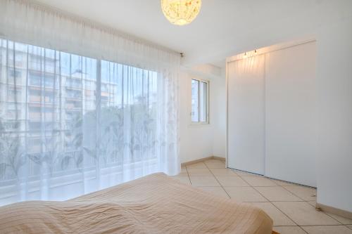 a bedroom with a bed and a large window at Angelina 2 pièces vue mer - Bej001 in Cros-de-Cagnes