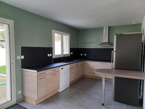 - une cuisine avec des murs verts, des placards en bois et une table dans l'établissement Maison de vacances 6 personnes, à Muron