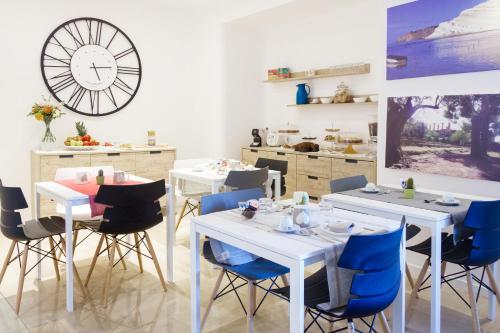 a restaurant with white tables and blue chairs and a clock at B&B Porta di Ponte in Agrigento