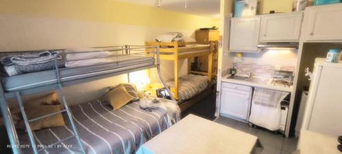 une petite chambre avec deux lits superposés et une cuisine dans l'établissement Charmant studio tout équipé Auron 4-5p, à Saint-Étienne-de-Tinée