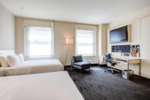 a hotel room with two beds and a desk and a tv at The Midland Hotel, Chicago, a Tribute Portfolio Hotel in Chicago