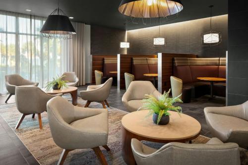 a waiting room with chairs and tables and a lobby at Courtyard By Marriott Titusville Kennedy Space Center in Titusville