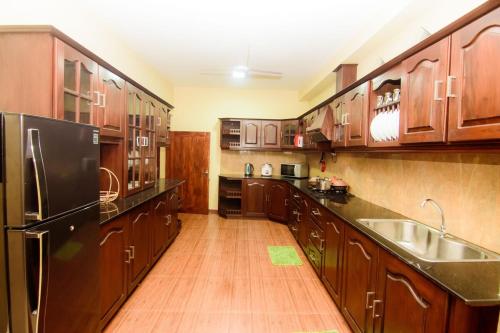 a kitchen with wooden cabinets and a black refrigerator at The House Dewata in Galle