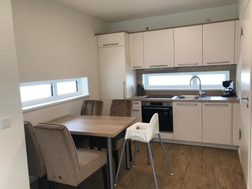 a kitchen with white cabinets and a wooden table and chairs at Hafen 15 - Ihre Ferienwohnung im Hafen am Geiseltalsee in Mücheln