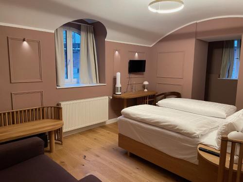 a bedroom with two beds and a desk and a television at Hotel Uhland in Munich