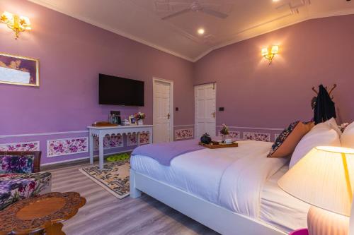a bedroom with a large bed and a tv at Seclude Tea Estate, Palampur in Pālampur